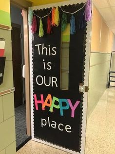 this is our happy place sign on the front door of a school hallway decorated with tassels