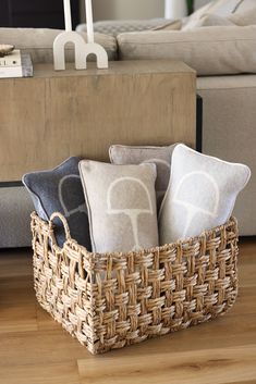 a basket filled with pillows sitting on top of a wooden floor