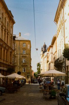 an old town street with tables and umbrellas