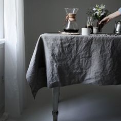 a table with a cloth on it and some coffee pots sitting on top of it