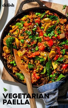 vegetarian paella in a cast iron skillet with a wooden spoon on the side