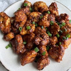 a white plate topped with fried chicken and green onions