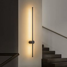 a wall light that is on the side of a stair case next to some stairs