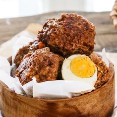 a wooden bowl filled with meat and an egg