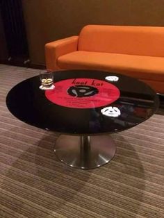 a glass table with stickers on it in front of an orange chair and couch