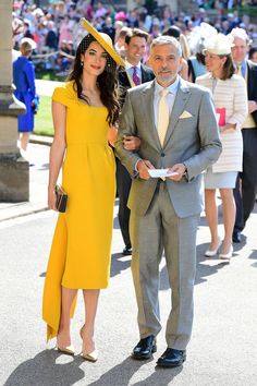 an older man and young woman in formal wear at a race event with people watching