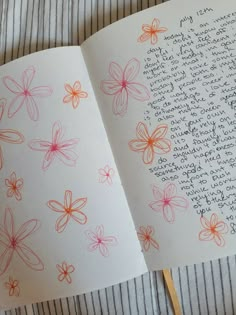 an open book with flowers drawn on it and writing in the pages next to a pair of scissors