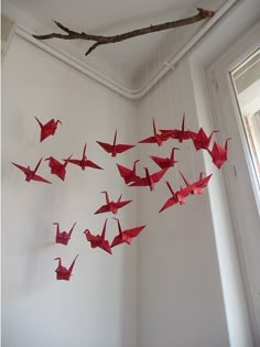 some red origami cranes hanging from a ceiling in a room with white walls