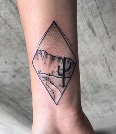 a black and white photo of a desert scene with a cactus tattoo on the ankle