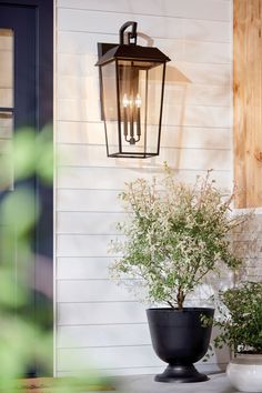 a light hanging from the side of a house next to a potted plant and door