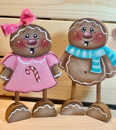 two gingerbread man standing next to each other on top of a wooden table with candy canes