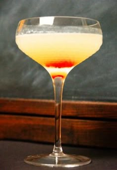 a glass filled with liquid sitting on top of a table next to a chalkboard