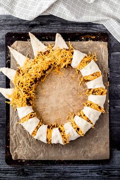 a cake with cheese and other toppings sitting on top of a wooden table next to a napkin