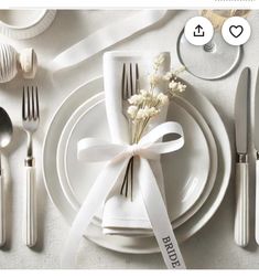 the table is set with white plates and silverware, wrapped in a satin ribbon