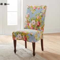 a blue floral chair sitting on top of a hard wood floor next to a window