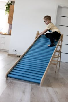 a young boy is playing on a blue slide