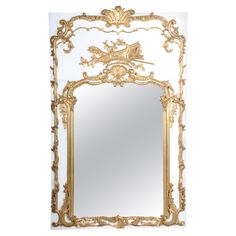 an ornate gold and white mirror on a white wall with the reflection of a bird in it