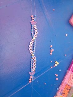 the beads are hanging from the string on the blue wall next to scissors and sprinkles