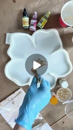 a person in blue gloves is making a flower out of plastic plates and paper towels