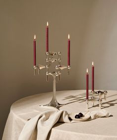 a table topped with candles and napkins on top of a white table cloth covered table