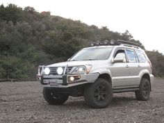 a white suv parked on top of a dirt field