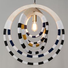 a circular light fixture made out of wood and painted with black, white, yellow and blue stripes