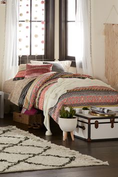 a bed sitting next to a window in a room with a rug on the floor