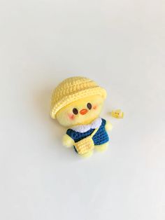 a small yellow stuffed animal with a hat and blue dress on it's chest