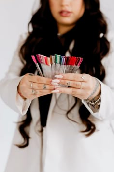 a woman holding a bunch of colored pencils in her hands