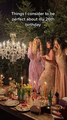 three women standing around a table with candles on it