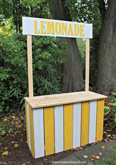 a lemonade stand with yellow and white stripes on the outside, in front of a tree