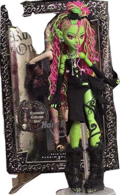 a doll with pink hair and green skin is posed in front of a black frame