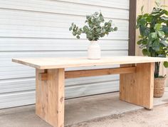 a wooden bench sitting next to a potted plant on top of a cement floor