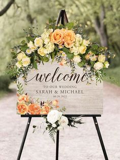 a welcome sign with flowers and greenery on it