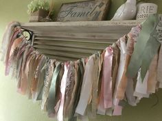 an old wooden frame with ribbons hanging from it's sides and flowers on top