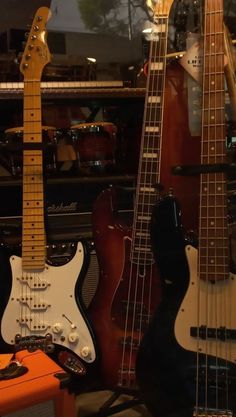 guitars are lined up on display in a music store, with other instruments behind them