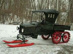 an old car is parked in the snow next to a pair of red skis