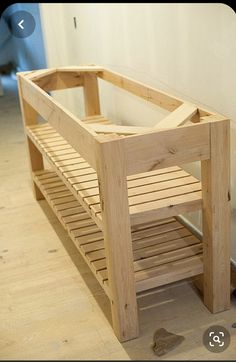 a wooden bench sitting on top of a hard wood floor next to a white wall