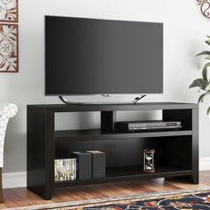 a flat screen tv sitting on top of a black entertainment center next to a white chair