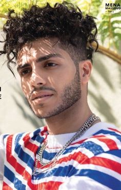 a young man with curly hair wearing a red, white and blue striped shirt looking at the camera