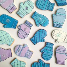 decorated cookies in the shape of mittens and gloves are displayed on a white surface