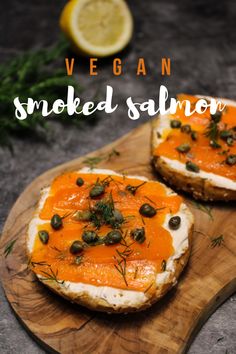 two pieces of bread topped with smoked salmon on top of a wooden cutting board next to lemon wedges