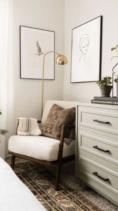 a bedroom with white furniture and pictures on the wall next to a chair, lamp, rug