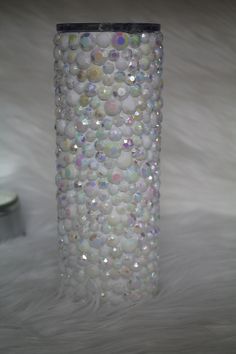 a white vase with lots of bubbles on it sitting on a fur covered floor next to a candle