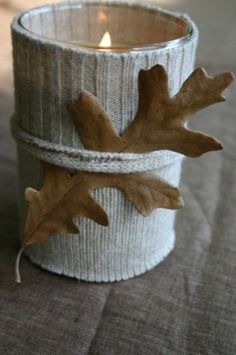 a candle that is sitting in a cup with some leaves on the inside of it