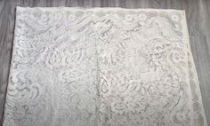 an old white lace tablecloth on a wooden floor