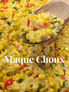 a wooden spoon scooping food out of a large pan filled with corn and vegetables