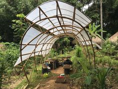 an outdoor shelter made out of bamboo sticks and other items on the ground in front of some trees