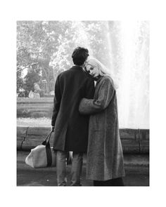 a man and woman standing in front of a fountain