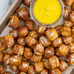 a tray filled with food next to a bowl of mustard and dipping sauce on top